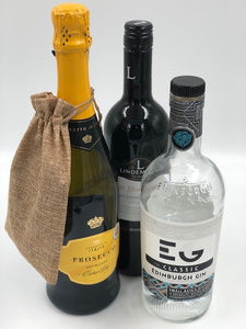 Hessian gift bag containing a personalised slate coaster hanging over a bottle of alcohol